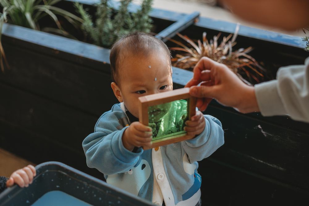 A baby holding a sensory frame up to the light