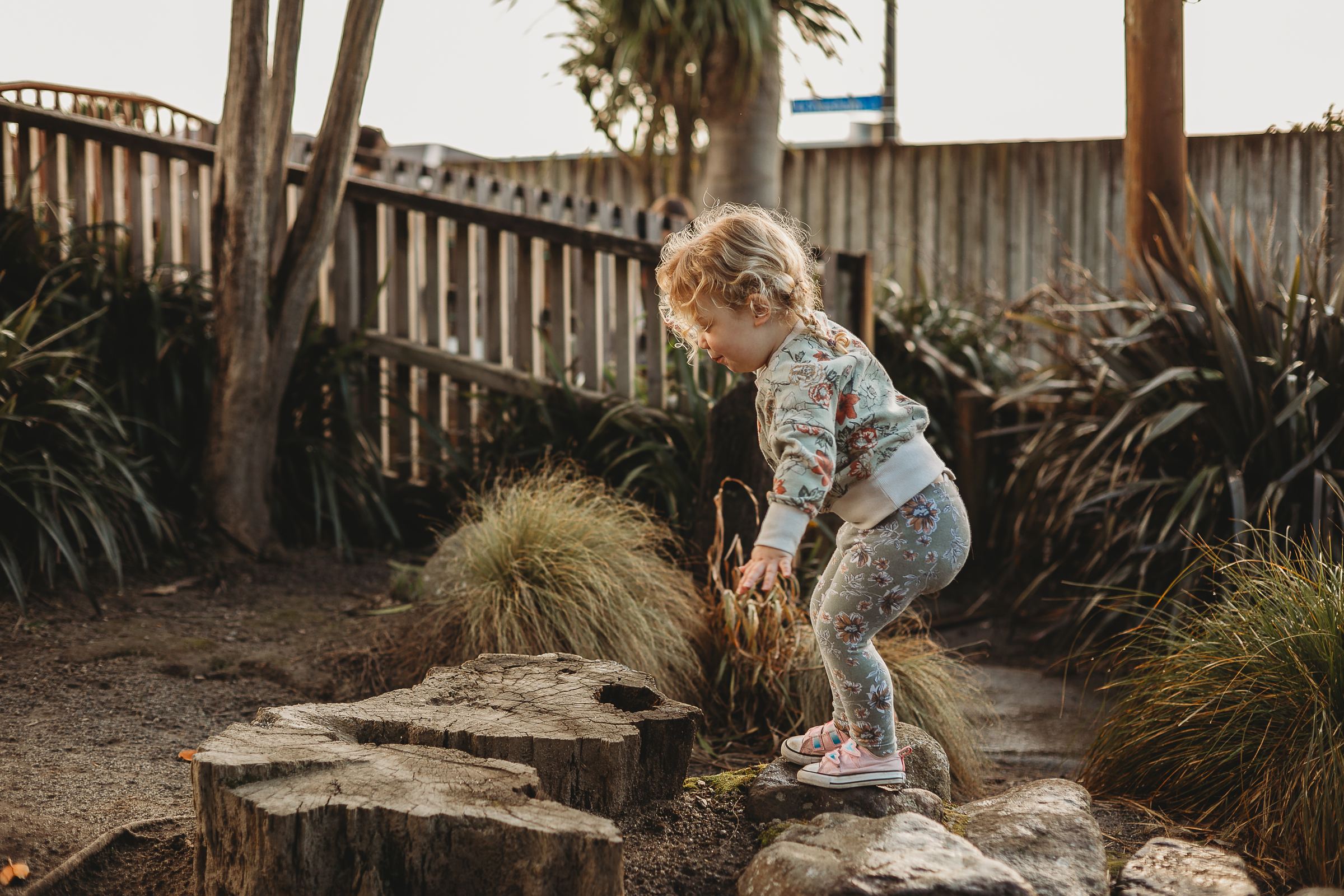 A young child stepping carefully through the native garden at Canopy