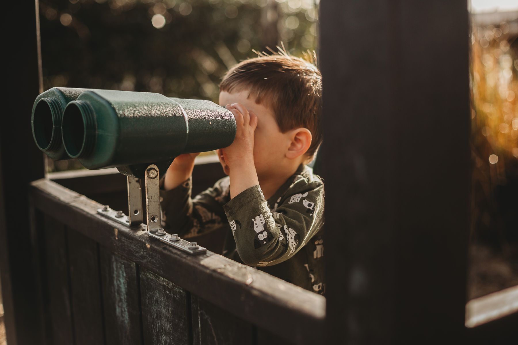 A boy looking out through garden binoculars